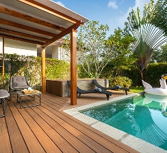 Villa privée luxe : terrasse bois, piscine turquoise Terrasse en bois et piscine privée luxueuse avec chaises longues, coin salon ombragé et décoration d'un cygne gonflable.
